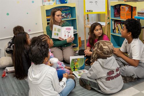 Students gathered around teacher reading book