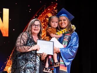 student posing with diploma