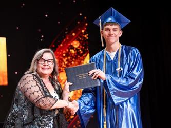 student posing with diploma