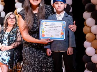 student posing with diploma