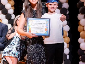 student posing with diploma