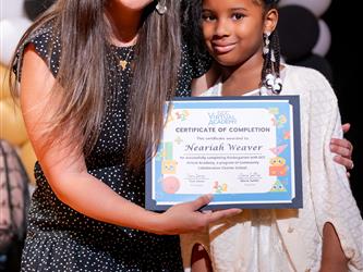 student posing with diploma