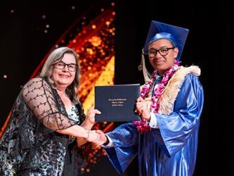 student posing with diploma