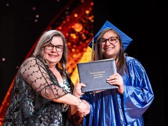 student posing with diploma