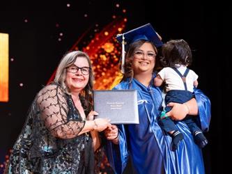 student posing with diploma