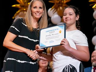 student posing with diploma