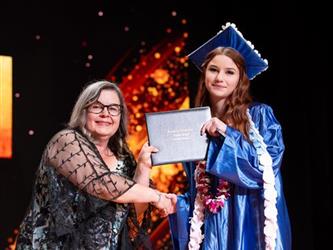 student posing with diploma
