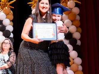 student posing with diploma