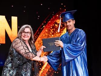 student posing with diploma