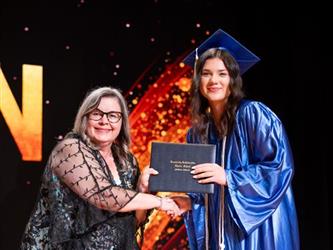 student posing with diploma