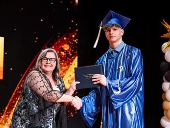 student posing with diploma