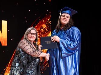 student posing with diploma