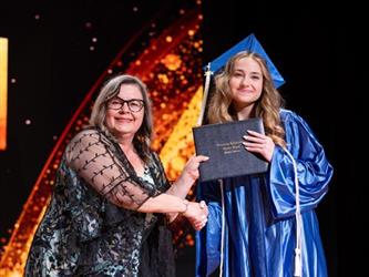 student posing with diploma