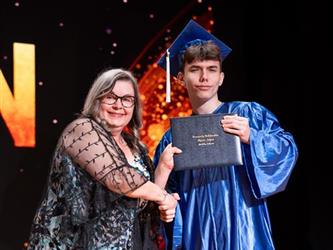student posing with diploma