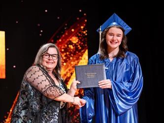 student posing with diploma