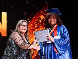 student posing with diploma