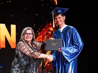 student posing with diploma