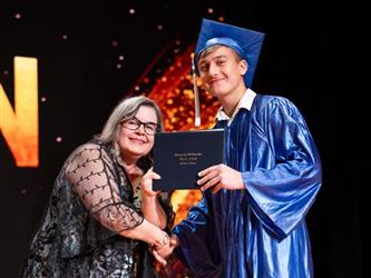 student posing with diploma
