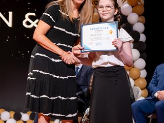 student posing with diploma