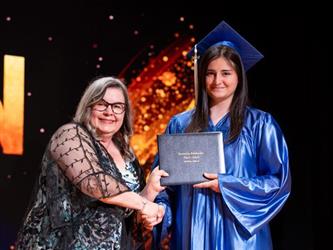 student posing with diploma
