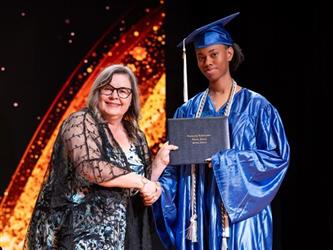student posing with diploma