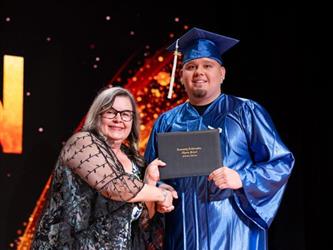 student posing with diploma