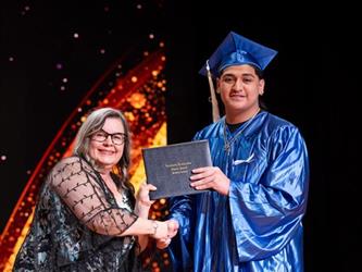student posing with diploma