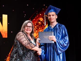 student posing with diploma