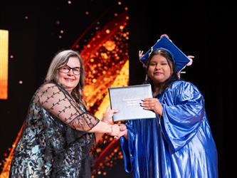 student posing with diploma