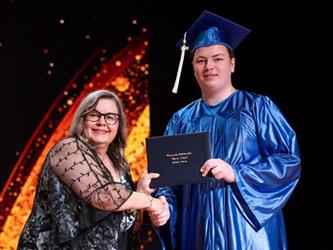 student posing with diploma