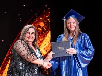 student posing with diploma