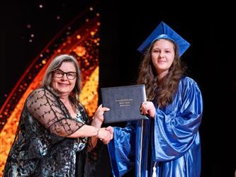 student posing with diploma