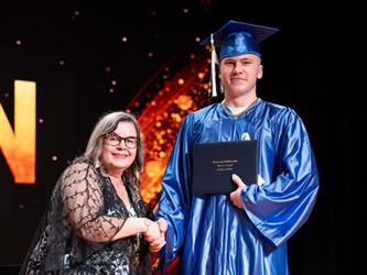 student posing with diploma