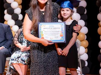 student posing with diploma