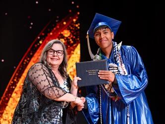 student posing with diploma