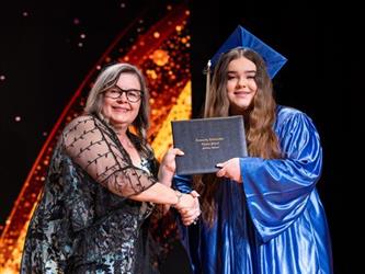 student posing with diploma