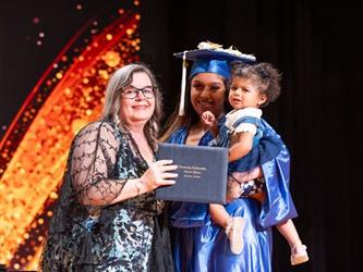 student posing with diploma