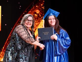 student posing with diploma