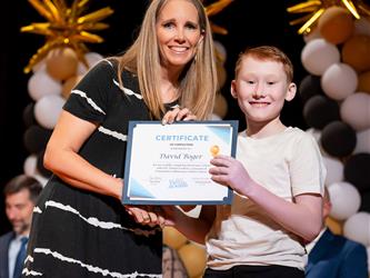 student posing with diploma