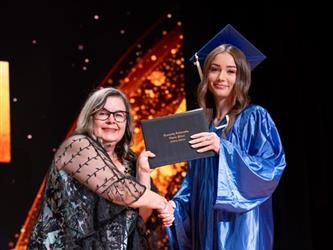 student posing with diploma