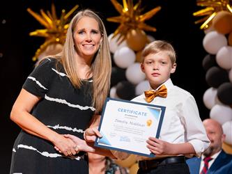 student posing with diploma