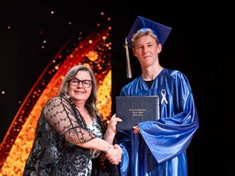 student posing with diploma