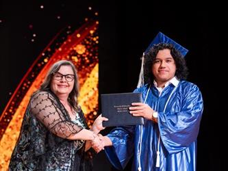 student posing with diploma