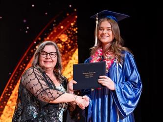 student posing with diploma