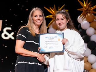 student posing with diploma