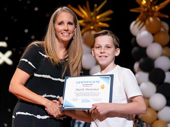 student posing with diploma