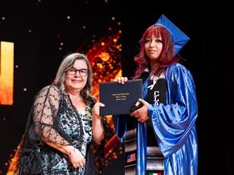 student posing with diploma